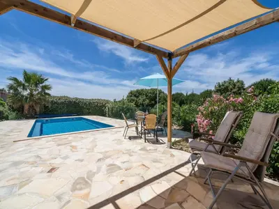 a patio with chairs and an umbrella and a swimming pool at Wine Country Family Villa in Félines-Minervois