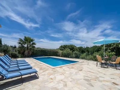 a swimming pool with chairs and a table and an umbrella at Wine Country Family Villa in Félines-Minervois