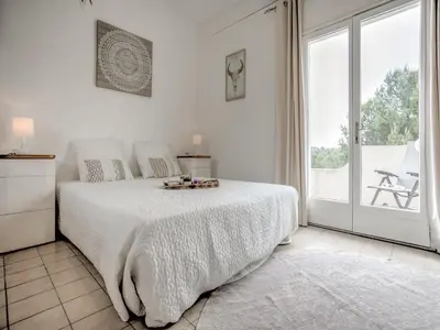 a white bedroom with a bed and a large window at Modern villa with private pool in Pouzols-Minervois