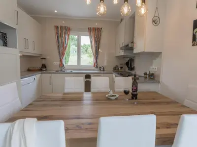 a kitchen with white cabinets and a wooden floor at Modern villa with private pool in Pouzols-Minervois