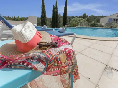 a hat and sunglasses sitting on a bench near a swimming pool at Modern villa with private pool in Pouzols-Minervois