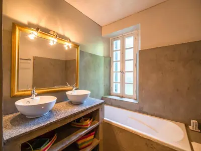 a bathroom with two sinks and a tub and a mirror at Stone House St Denis with Pool & Views in Saint-Denis
