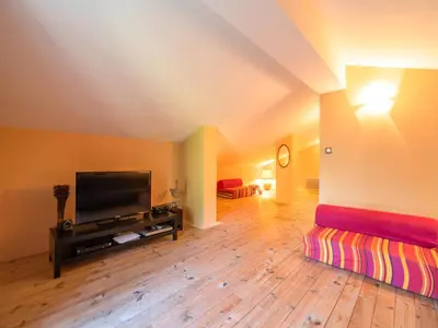 a living room with a flat screen tv on a wooden floor at Stone House St Denis with Pool & Views in Saint-Denis