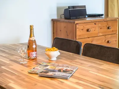 a bottle of wine and a magazine on a wooden table at Modern Villa with Heated Pool in Beaufort