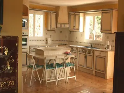 a kitchen with white cabinets and a table and chairs at Hillside Retreat in Roquebrun in Roquebrun