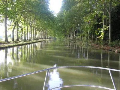 a boat traveling down a river with trees on it at Villa in Beaufort with Private Pool in Beaufort