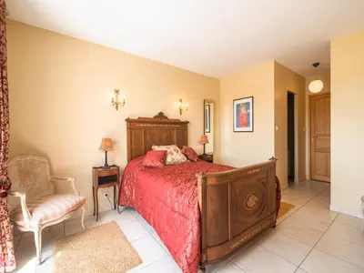 a bedroom with a bed and a chair at Villa in Limoux with Private Pool & Mountain Views in Limoux