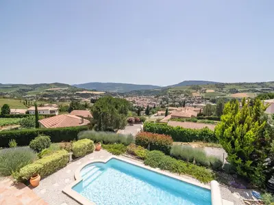 a swimming pool in a garden with a view of a city at Villa in Limoux with Private Pool & Mountain Views in Limoux