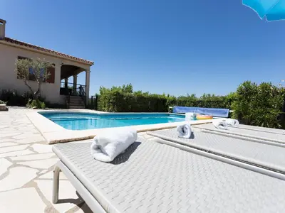 a white bed next to a swimming pool at Villa near Carcassonne with Heated Pool in Félines-Minervois