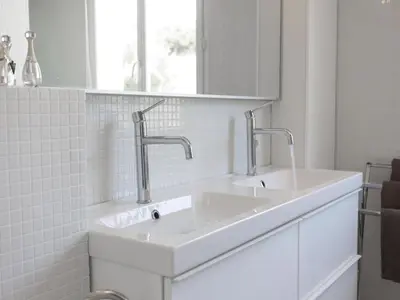 a white bathroom with two sinks and a mirror at Villa in Castelnau d'Aude with Heated Pool in Castelnau-dʼAude