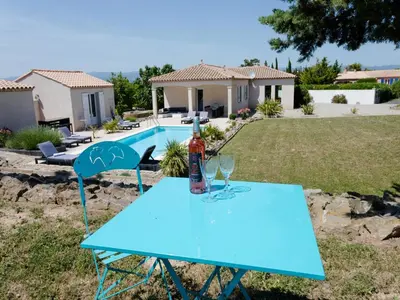 a blue table with a bottle of wine and two glasses at Villa in Castelnau d'Aude with Heated Pool in Castelnau-dʼAude