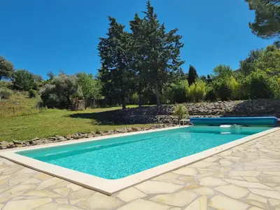 a swimming pool in a yard with a rock wall at Villa in Castelnau d'Aude with Heated Pool in Castelnau-dʼAude