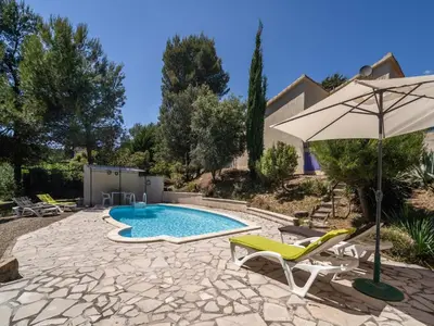a patio with a pool and an umbrella and chairs at Villa in Pouzols with Private Pool in Pouzols-Minervois