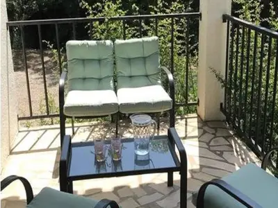 a chair on a balcony with two glasses on a table at Spa Oasis Near Canal du Midi in Félines-Minervois
