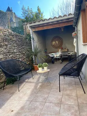 a patio with two chairs and a table and a stone wall at Côte de la Cité in Carcassonne