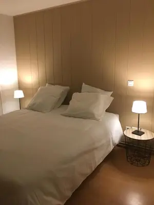 a bed with white sheets and pillows and two lamps at Côte de la Cité in Carcassonne