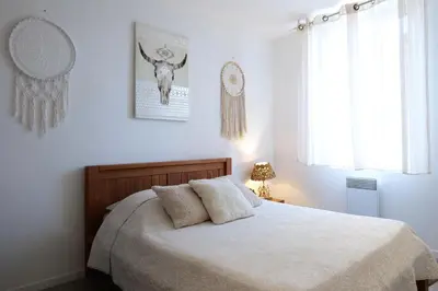 a bedroom with a bed with white sheets and a window at Gîte proche du canal du midi et Narbonne 2 chambres in Mirepeisset