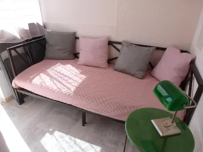 a small bed with pink pillows and a green table at La Pergola de la Plage in Gruissan