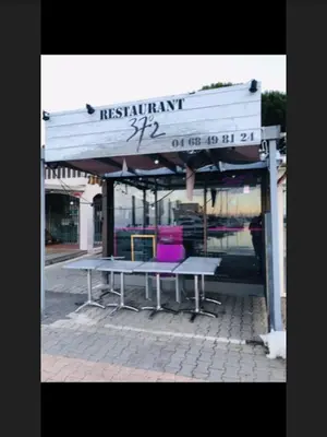 a bus stop with two tables and a purple at La Pergola de la Plage in Gruissan