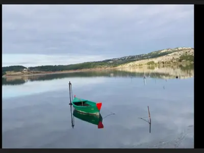 a green boat sitting in the middle of a lake at La Pergola de la Plage in Gruissan