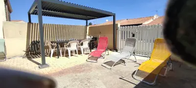 a group of chairs and a table in a patio at Gite Rouge à la mer climatisation dans toutes les pièces in Port-la-Nouvelle