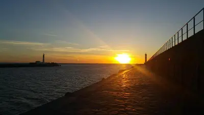 a sunset over a body of water with a fence at Gite Rouge à la mer climatisation dans toutes les pièces in Port-la-Nouvelle