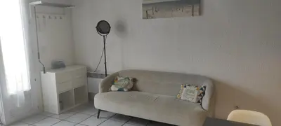 a living room with a couch and a lamp at Gite Rouge à la mer climatisation dans toutes les pièces in Port-la-Nouvelle