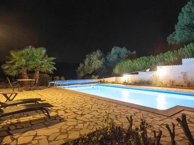a swimming pool at night with a table and chairs at Charming French Villa with Pool in Cébazan