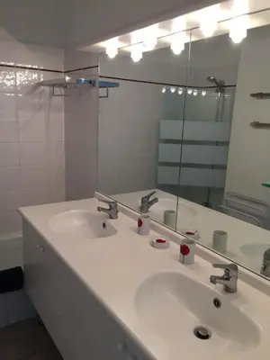a bathroom with two sinks and a large mirror at T 3 appart les jardins du phœbus in Gruissan