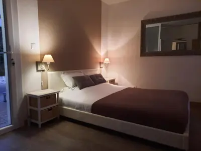 a bedroom with a large bed and a mirror at 15min de la Cité de Carcassonne dans petit village, chambre au calme, petit-déjeuner et jacuzzi en supplément in Carcassonne