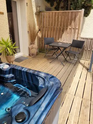 a hot tub on a deck with a table and chairs at 15min de la Cité de Carcassonne dans petit village, chambre au calme, petit-déjeuner et jacuzzi en supplément in Carcassonne