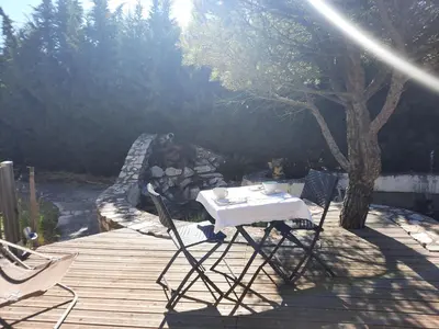a table and chairs sitting on a wooden deck at 15min de la Cité de Carcassonne dans petit village, chambre au calme, petit-déjeuner et jacuzzi en supplément in Carcassonne