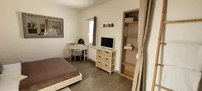 a bedroom with a bed and a desk with a television at 15min de la Cité de Carcassonne dans petit village, chambre au calme, petit-déjeuner et jacuzzi en supplément in Carcassonne