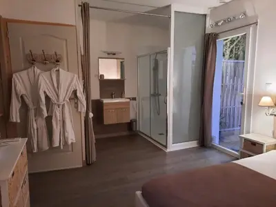 a hotel room with a robe hanging on a door at 15min de la Cité de Carcassonne dans petit village, chambre au calme, petit-déjeuner et jacuzzi en supplément in Carcassonne