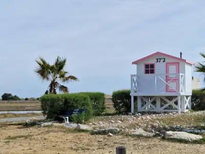 a pink lighthouse on the beach with a palm tree at Gruissan Village APPT Duplex 51m2 in Gruissan