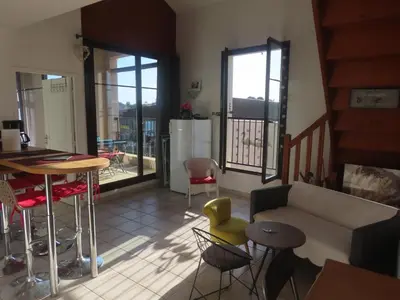 a living room with a couch and a table and chairs at Gruissan Village APPT Duplex 51m2 in Gruissan