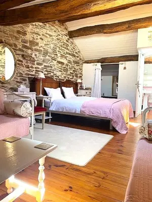 a bedroom with a large bed and a stone wall at Chez Providence Chambres et Table d'Hôtes in Cuxac-Cabardès