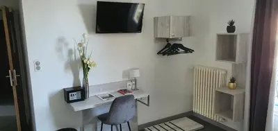 a room with a desk and a television on a wall at Hôtel L'Alsace in Narbonne