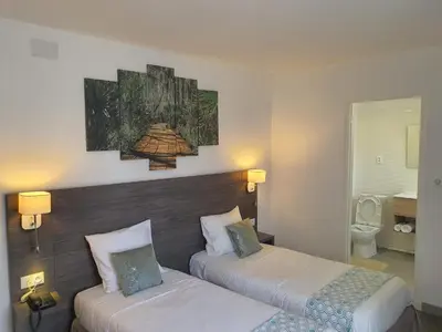 a hotel room with two beds and a bathroom at Hôtel L'Alsace in Narbonne