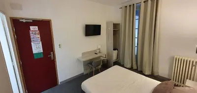 a hotel room with a bed and a desk at Hôtel L'Alsace in Narbonne