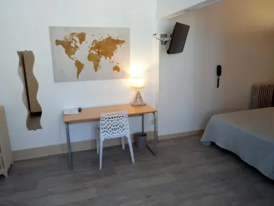 a room with a desk with a lamp and a map on the wall at Hôtel Rivière in Castres