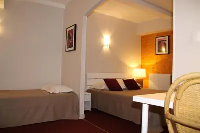 a hotel room with two beds and a table and a desk at Hôtel Rivière in Castres
