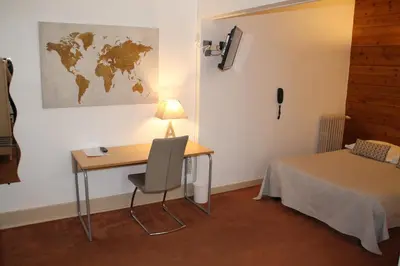 a room with a desk and a table and a bed at Hôtel Rivière in Castres