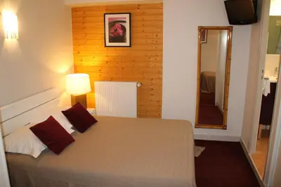 a bedroom with a large bed and a mirror at Hôtel Rivière in Castres