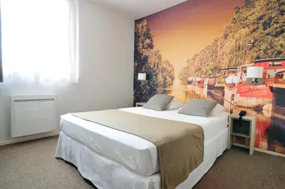 a bedroom with a large bed with a painting on the wall at Relais Fasthotel Port Lauragais in Avignonet-de-Lauragais