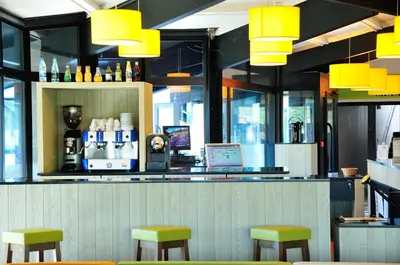 a bar with yellow stools in a restaurant at Relais Fasthotel Port Lauragais in Avignonet-de-Lauragais