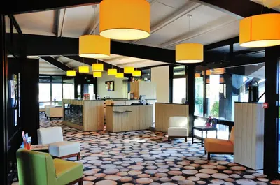 a lobby with chairs and tables and yellow lights at Relais Fasthotel Port Lauragais in Avignonet-de-Lauragais