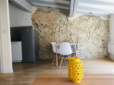 a kitchen with a stone wall and a table and chairs at Au pied de la Cité in Carcassonne