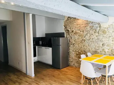 a kitchen with a table and a stone wall at Au pied de la Cité in Carcassonne