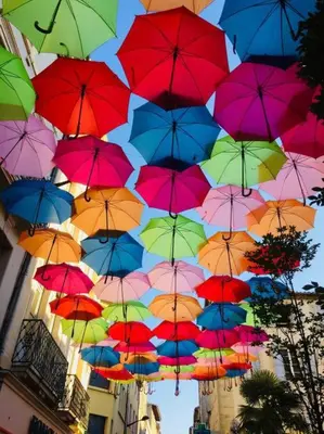 a bunch of colorful umbrellas hanging in the air at Au pied de la Cité in Carcassonne